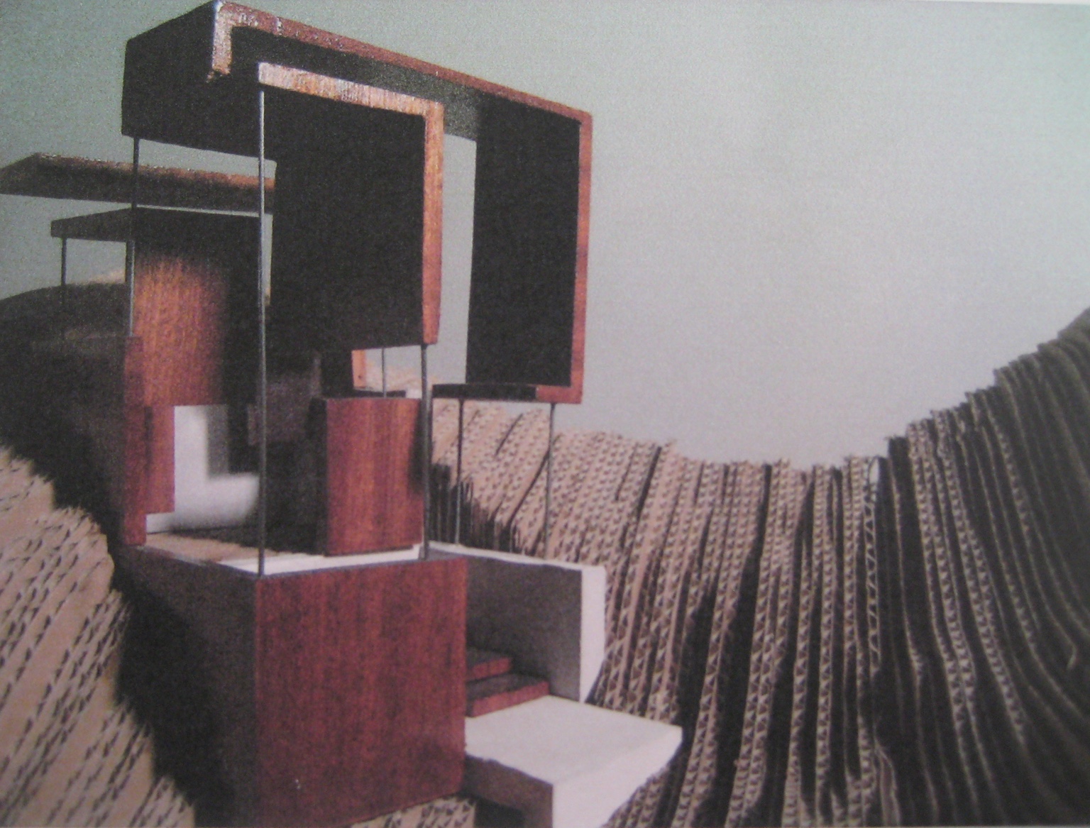 Physical architectural model with stacked geometric volumes and slender supports set within a contoured landscape.